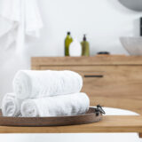 Rolled Bath Towels On Tub Tray In Bathroom. Space For Text