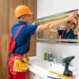 Male repairman hangs the modern electronic bathroom mirror. accessories and furniture for bathrooms and houses