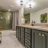 Green is the theme in this beautiful bathroom with brass faucets and fixtures