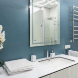 Blue And White Bathroom With Big Mirror, Towels, Lighting And Co